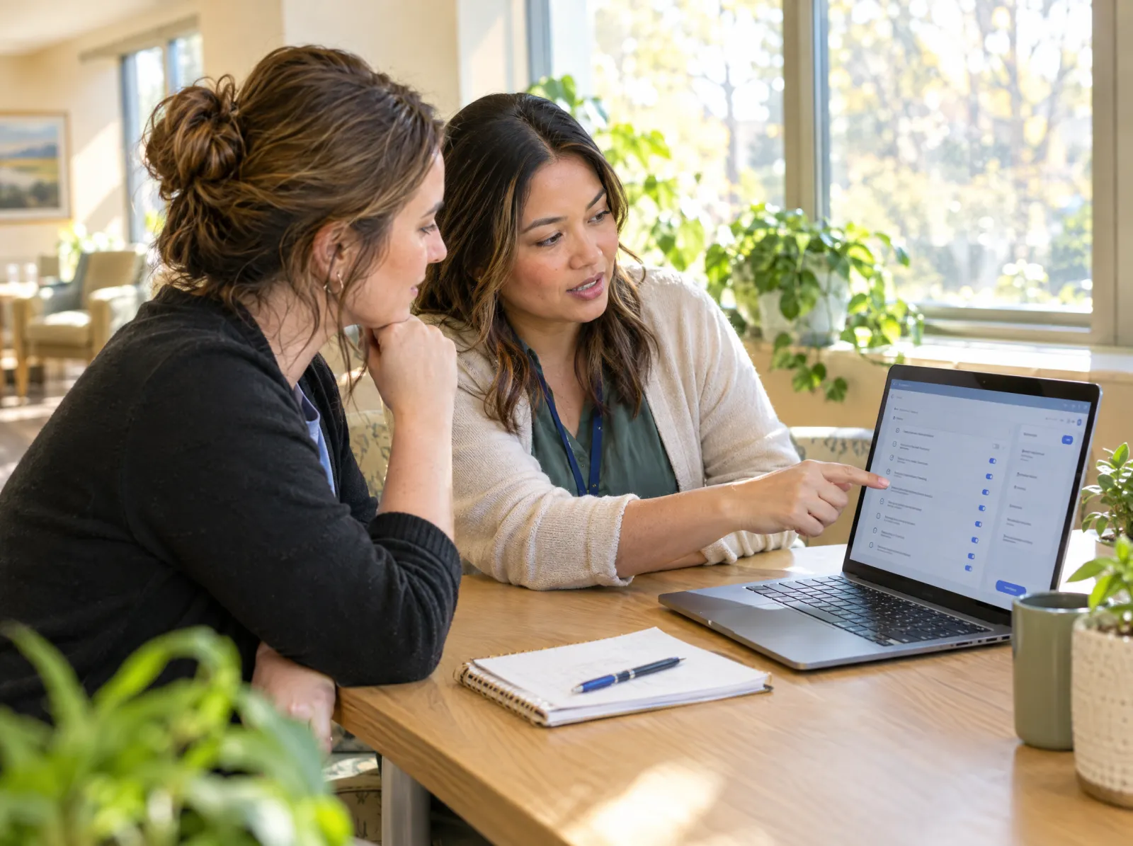 Two admissions coordinators review criteria on a laptop together
